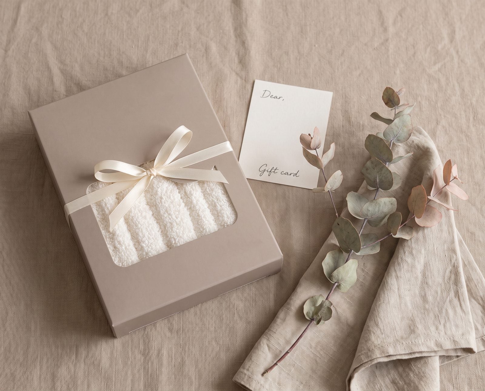 Toe Dry Towel box tied with a cream ribbon beside a gift card